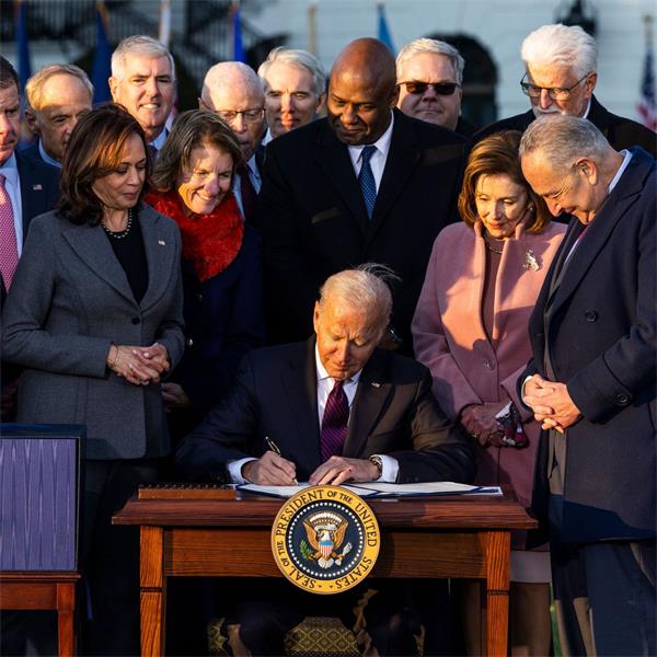President Biden at desk surrounded by Cabinet members
